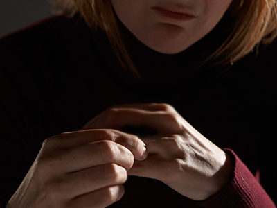 A worried woman holds her ring finger- she's been through a divorce.