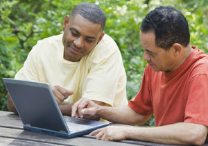 Two men use a laptop computer