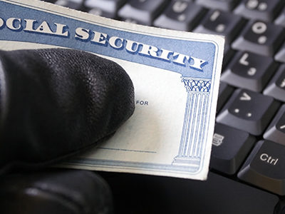 An identity thief holds a Social Security card in front of a keyboard