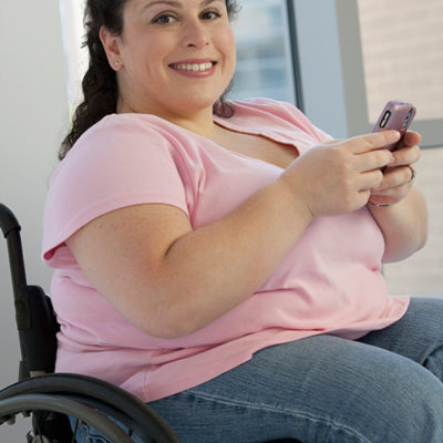 Woman in wheelchair smiling using smartphone