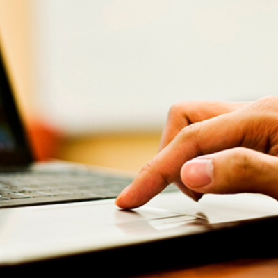 A man's hand on a touchpad of a laptop