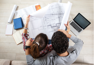 photograph of a couple looking at the blueprint of a house, planning for their future.