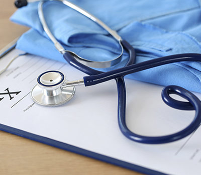 Prescription form clipped to pad lying on table with stethoscope twisted in heart shape and blue doctor uniform closeup. Medicine or pharmacy concept. Empty medical form ready to be used