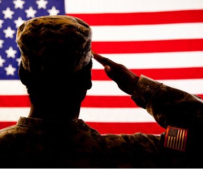 silhouette of a soldier standing in front of the american flag and saluting,