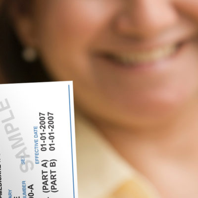 A woman holds up a Medicare card