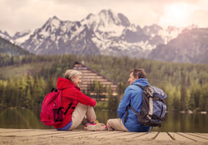 A man and woman with backpacks, looking at a mountain
