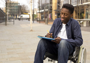 young man in a wheelchair writing a letter