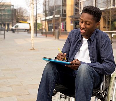 A man writing in wheelchair