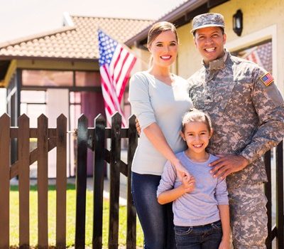 A military family posing for a photo outside their home