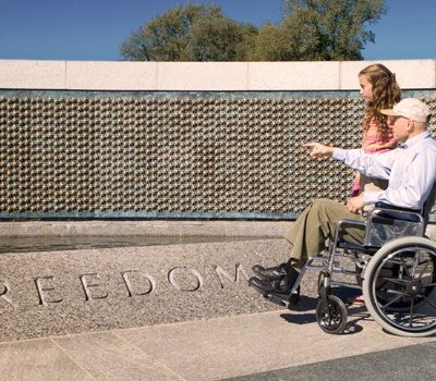A man in wheel chair and woman looking at a war memorial
