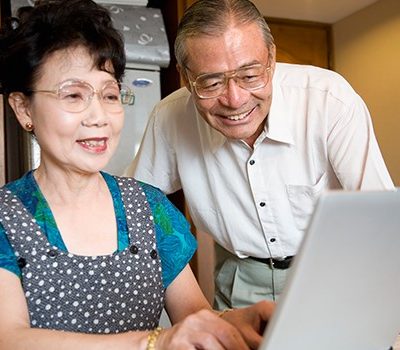 An elderly couple using a laptop in a kitchen