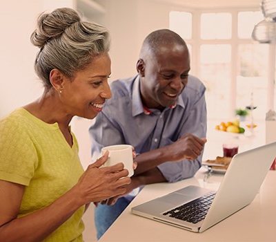 A couple using a laptop at a breakfast bar in a kitchen