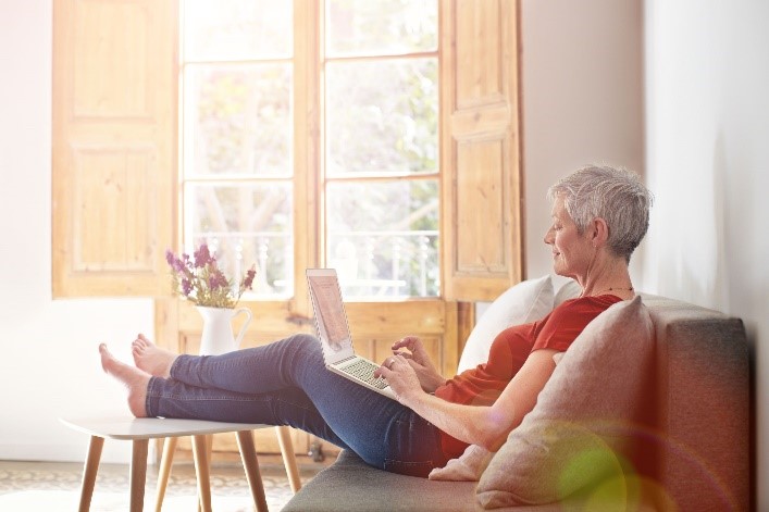 woman relaxing on couch, using laptop 