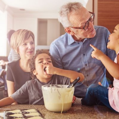 A grandfather and grandkids baking cookies in a kitchen