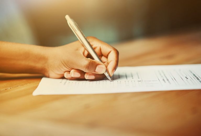 A hand filling out a document with a pen