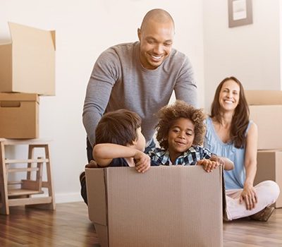 A family sharing a genuine moment while sitting on the floor of a living room with moving boxes