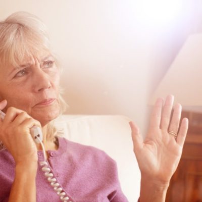 An older woman talking on a telephone