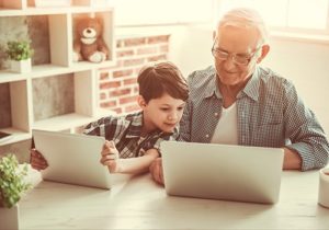 A grandfather and grandson looking at a laptop.