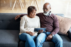 An older couple watching a video together on a tablet device.