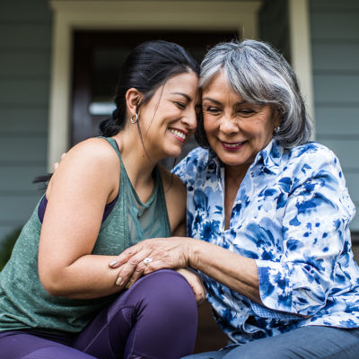 Senior woman and adult daughter laughing on porch