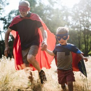 grandfather and grandson running together in super hero costumes