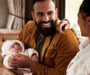 father holding a newborn baby smiling with the mother