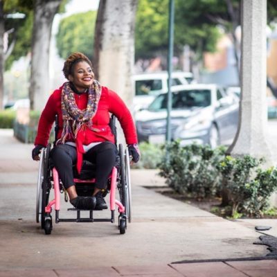 woman in a wheelchair going down a sidewalk