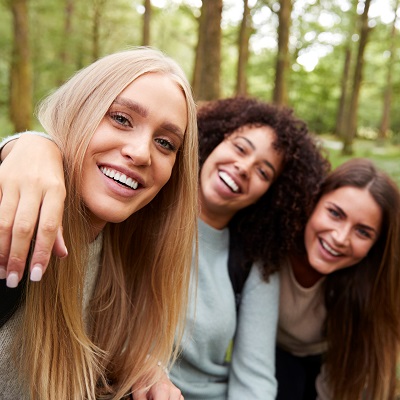 Three young adult women taking a selfie in a forest during a hike, close up