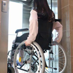 Woman in wheelchair entering elevator back view