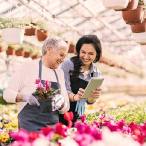 women business owner working in a flower shop reviewing items on a pad with another owner