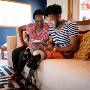 A mother and son sitting on a couch while looking at a tablet device