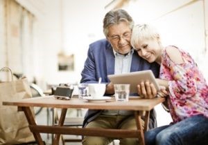 Pareja de esposos sentados en la mesa tomando un café y usando una tableta para leer el artículo